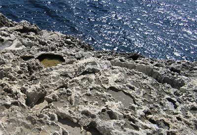 A água da chuva é um ácido muito fraco. Ele pode dissolver calcário e outras rochas carbonáticas deixando para trás poços e buracos. Wied-iz-zurrieq, Malta. © Richard Burt